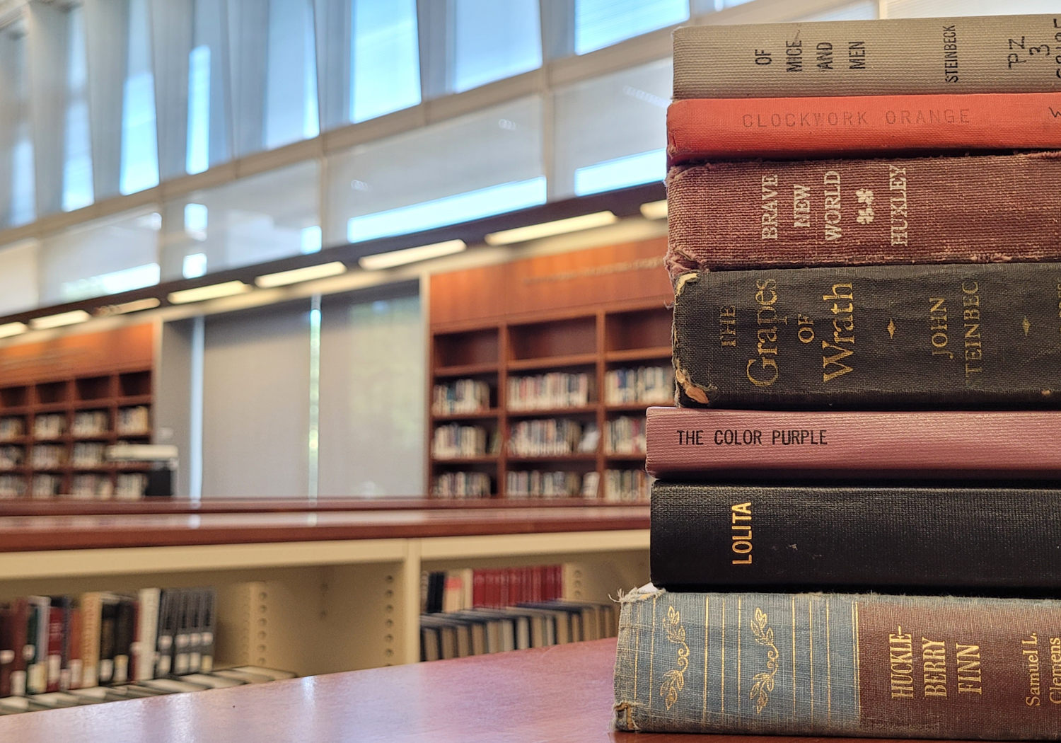 Image shows a stack of books against a blurred background of library shelves.