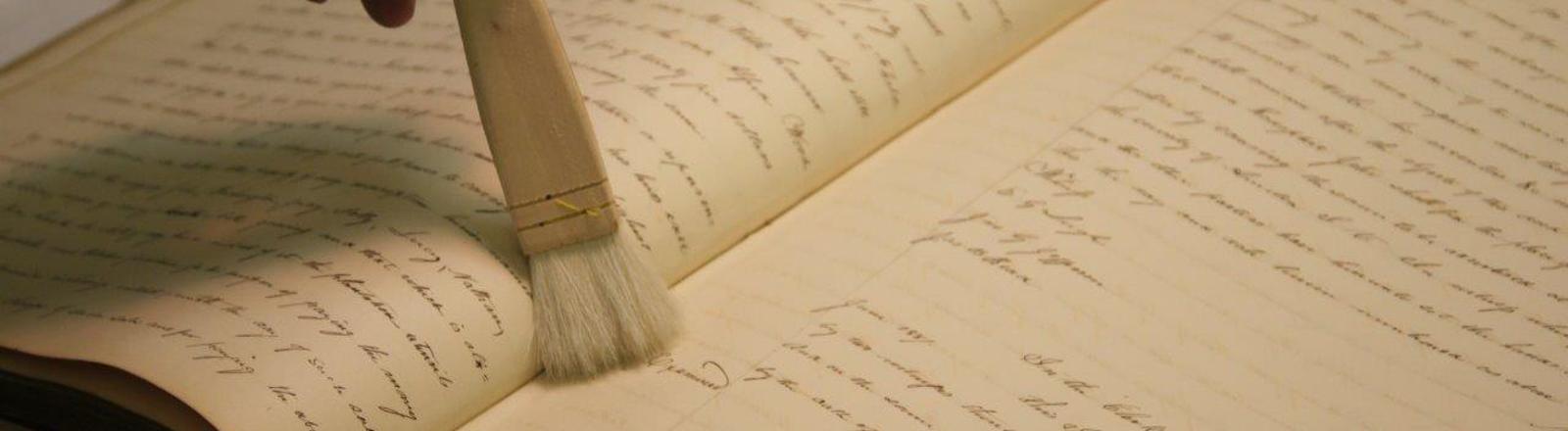 Bound volume laying open with shot soft bristled conservation brush held atop the the right page